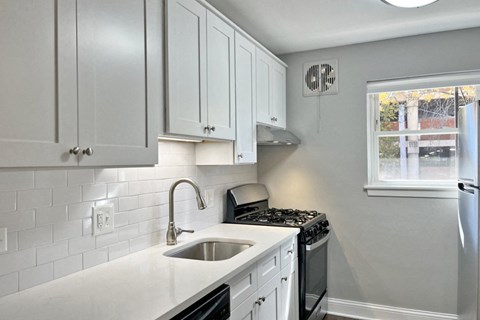 a kitchen with white cabinets and a sink and a window