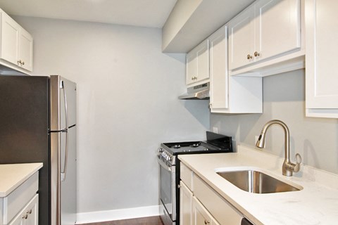 A kitchen with a refrigerator, stove, and sink.