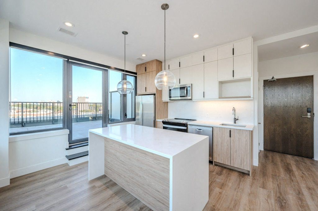 a white kitchen with a large island and a balcony