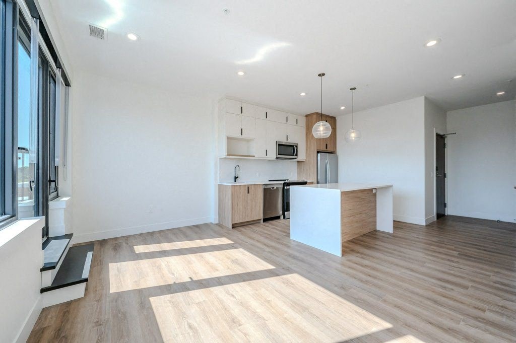 an open kitchen and living room with wood floors and white walls