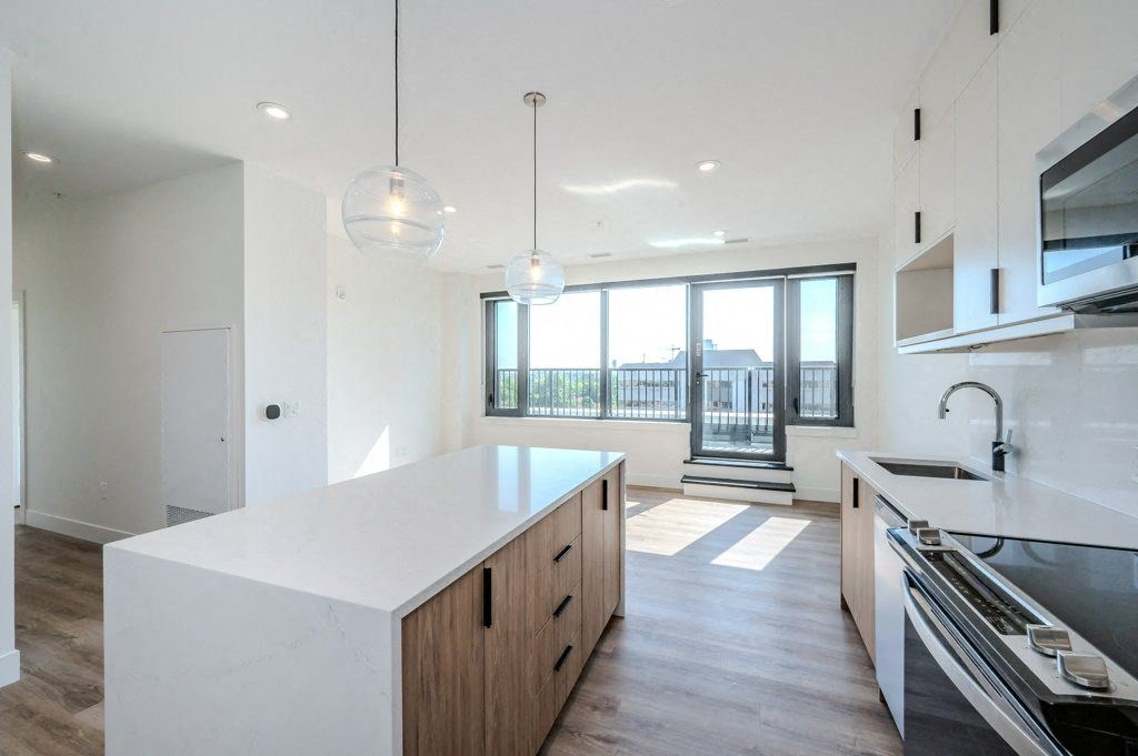 a white kitchen with a large island and a balcony