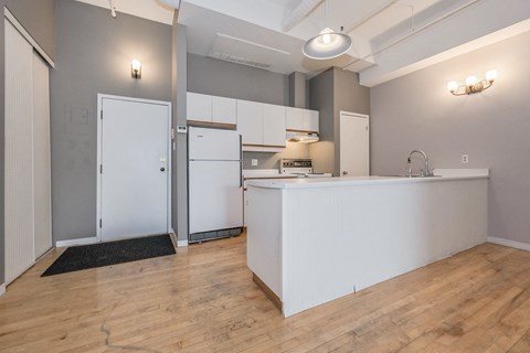 A kitchen with a white counter and wooden floors.