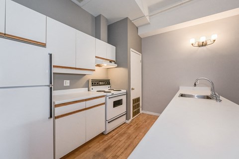 A kitchen with white cabinets and a stainless steel refrigerator.