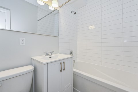 A white bathroom with a tub, sink, and medicine cabinet.