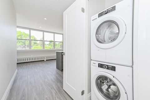 A white washing machine is on top of a white dryer in a laundry room.