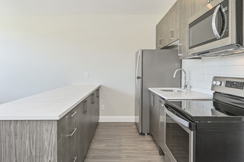 A kitchen with a refrigerator, oven, and microwave.