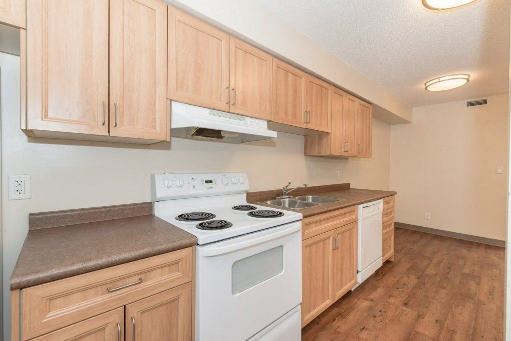 A kitchen with wooden cabinets and a white stove top oven.