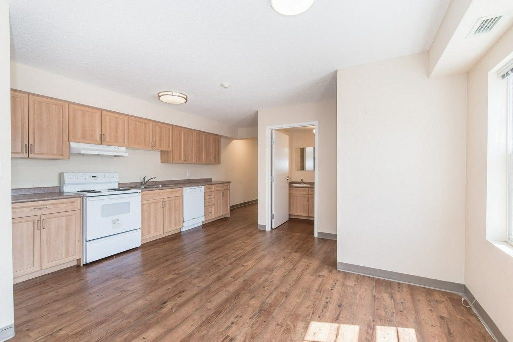 A kitchen with wooden floors and white appliances.