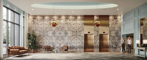 Two people are standing in a lobby with a marble wall and gold elevators.