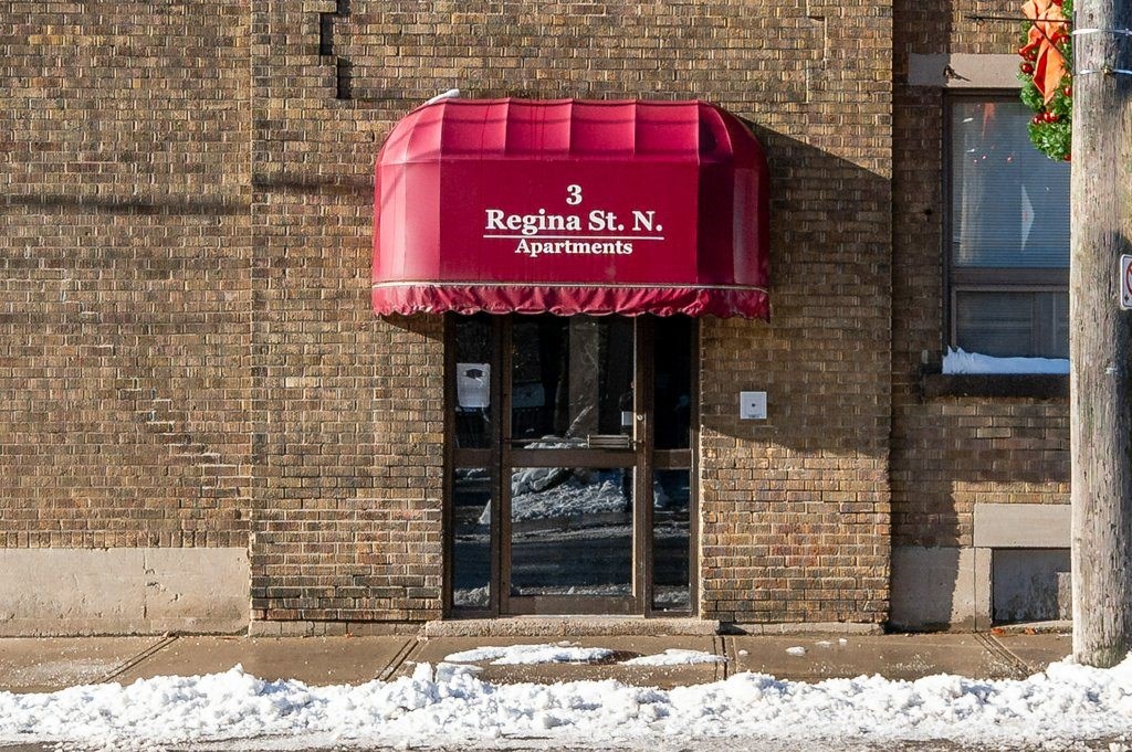 A building with a red awning that says Regina St. Apartments.