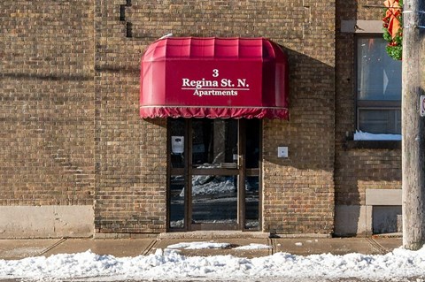 A building with a red awning that says Regina St. Apartments.
