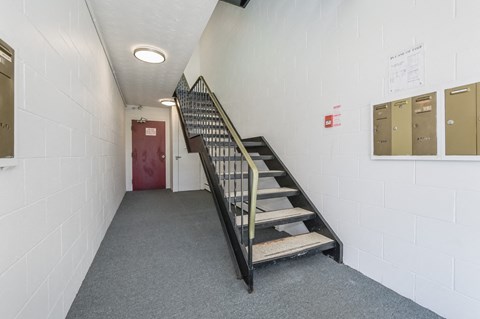 A staircase with a metal railing and a red door at the top.