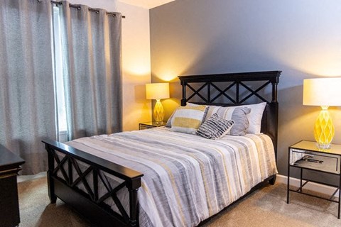 A bedroom with a bed, nightstand, and lamp.