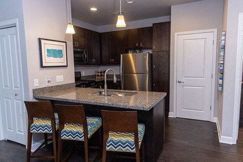 A kitchen with a granite countertop and a stainless steel refrigerator.
