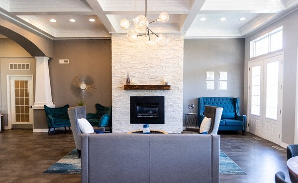 A living room with a fireplace and a grey couch.
