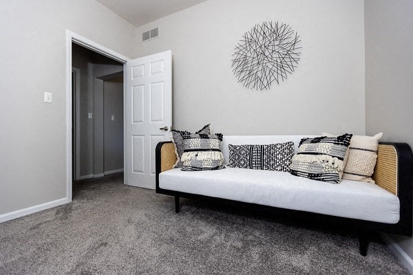 A black and white couch with pillows sits in a room with a white door and a wall art.