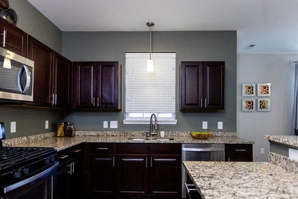 A kitchen with dark brown cabinets and granite countertops.