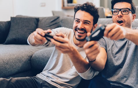 Two men are playing video games on a couch.