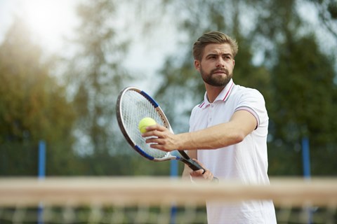 A man in a white shirt is holding a tennis racket and ball.