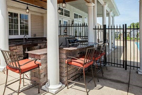 Patio grilling area with a bar and chairs and resident pool at Prairie Point Apartments