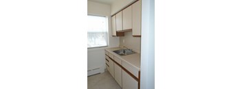 a kitchen with white cabinets and a sink and a window