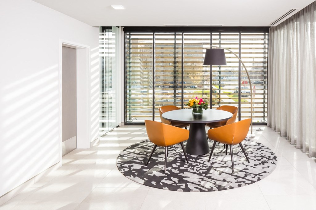 a dining area with a round table and four orange chairs