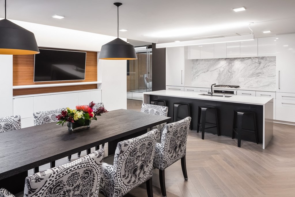 a dining area with a wooden table and chairs and a black and white kitchen in the background