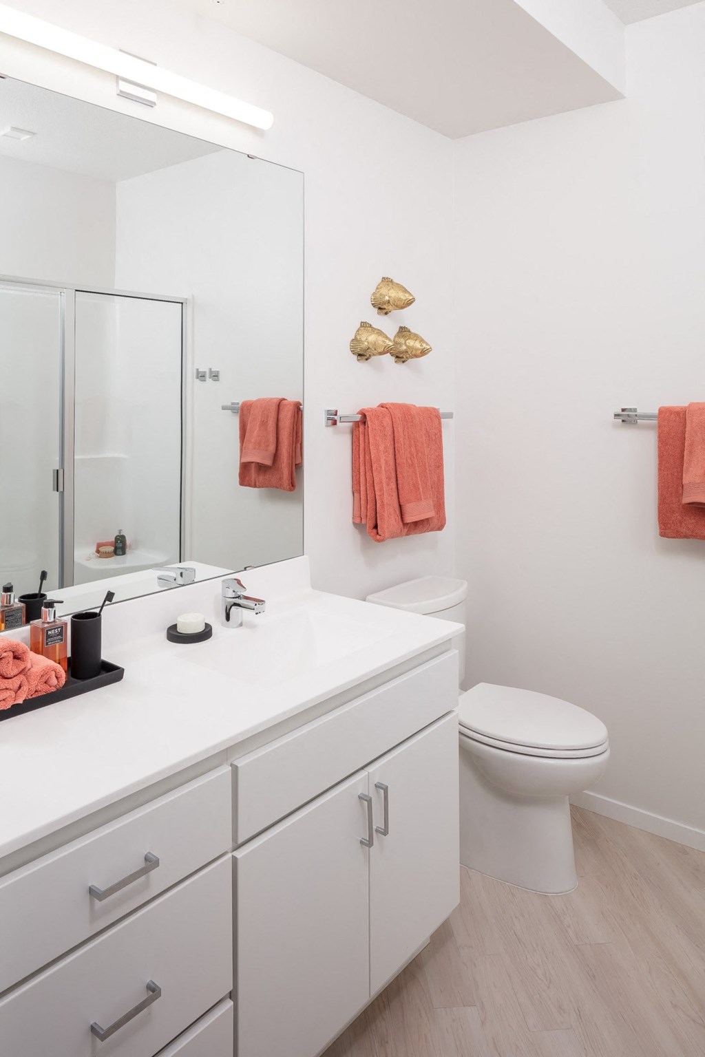 a bathroom with a white sink and toilet next to a large mirror