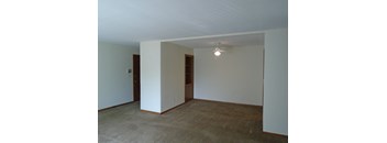 an empty living room with white walls and a ceiling fan