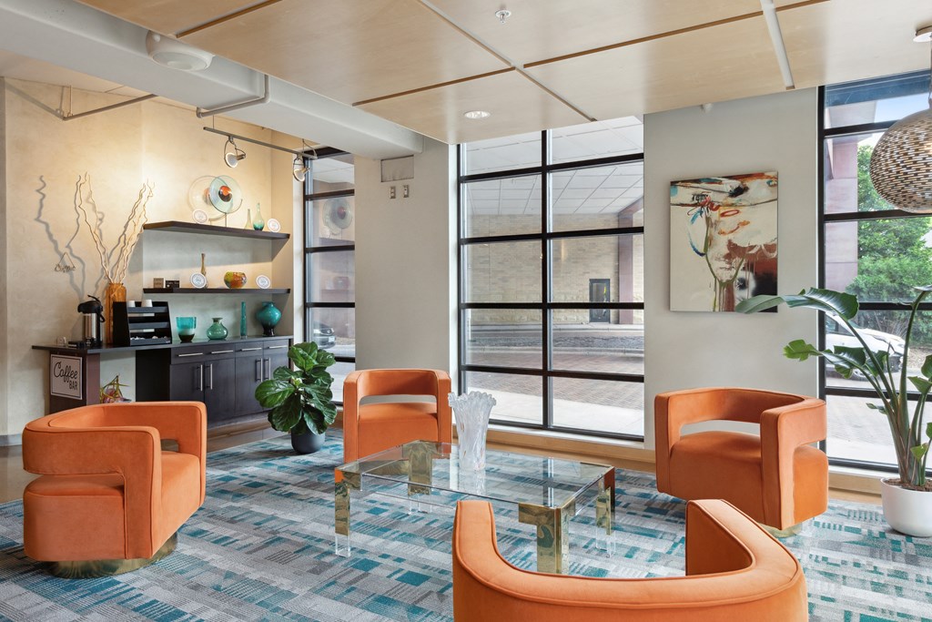 a living room with orange chairs and a glass coffee table
