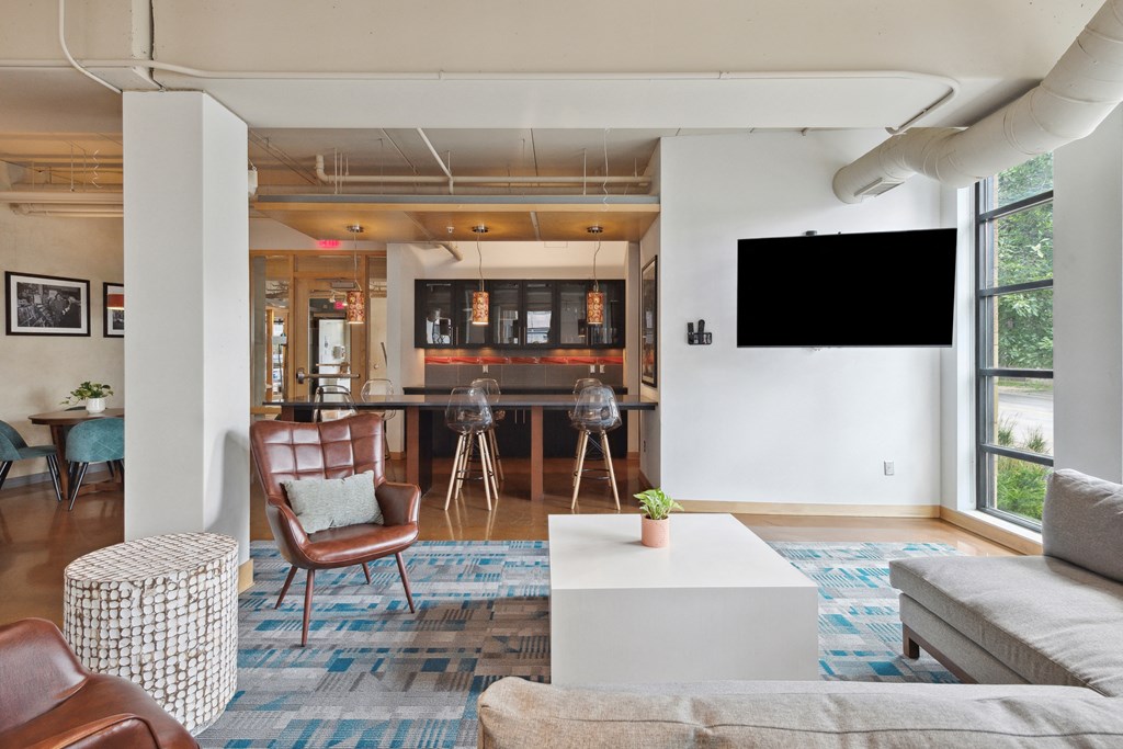 a living room with a large screen tv on the wall and a kitchen in the background
