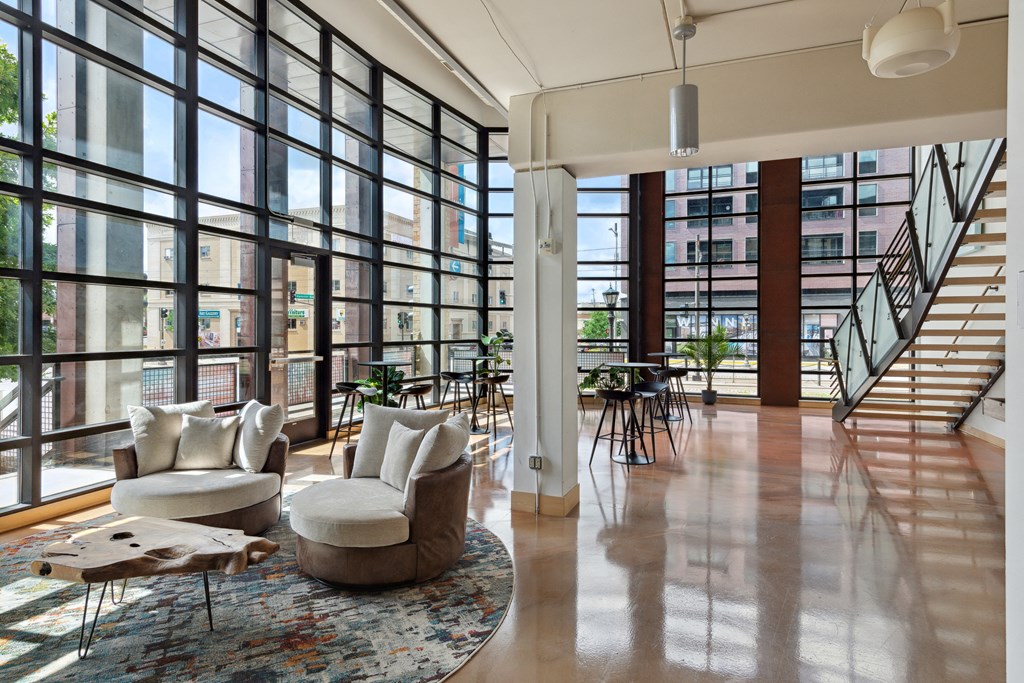 a large living room with floor to ceiling windows and a staircase to the second floor