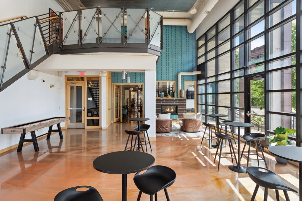 a large room with tables and chairs and a staircase in the background