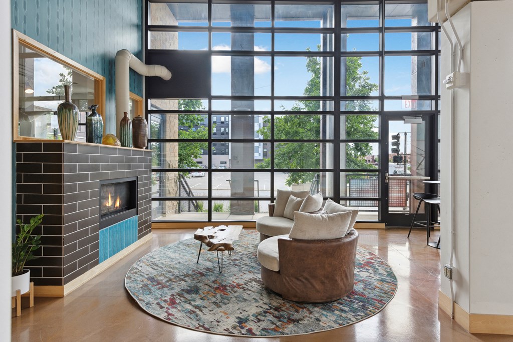 a room with two oversize brown chairs in front of  a fireplace and a large window