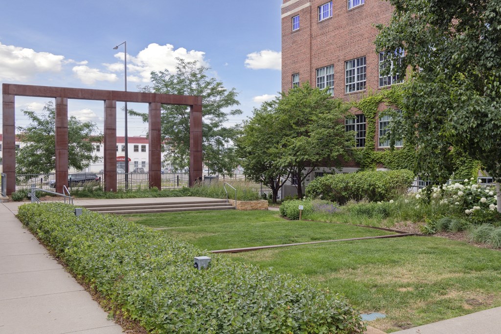 a grassy area in front of a brick building with a large wooden structure in the background