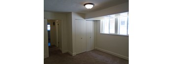 an empty living room with white cabinets and a window