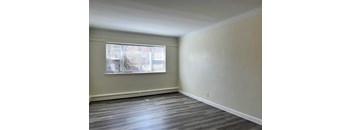an empty living room with a window and wood floors
