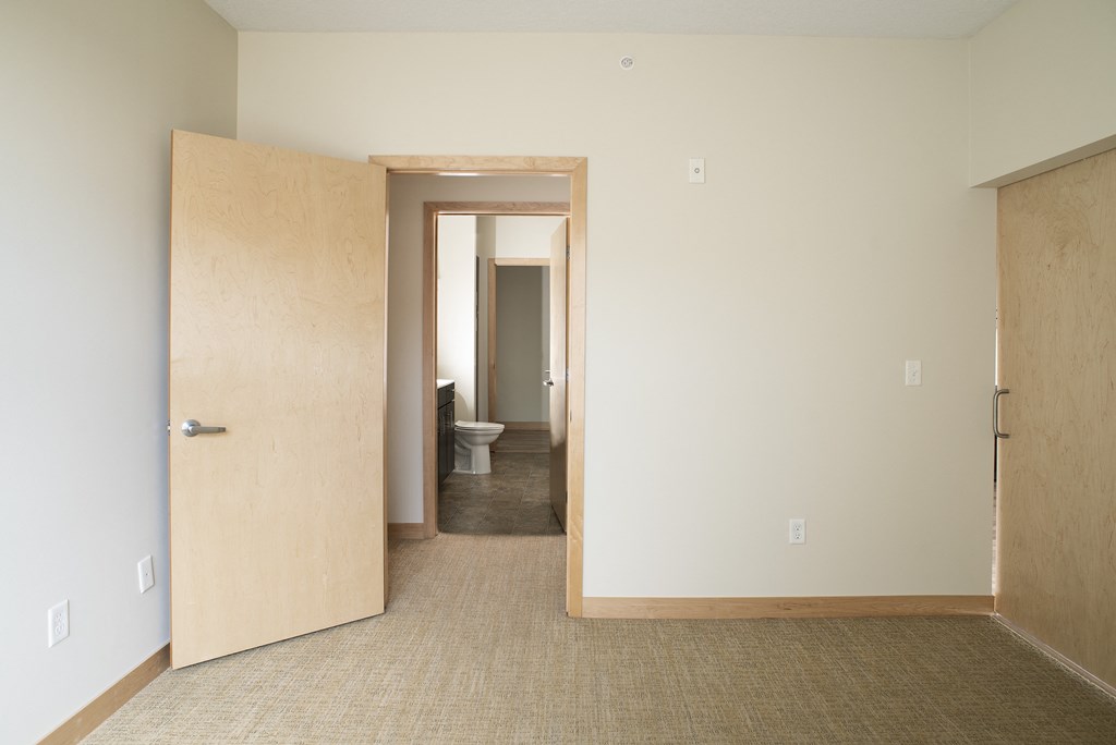 an empty room with a door to a bathroom and a toilet