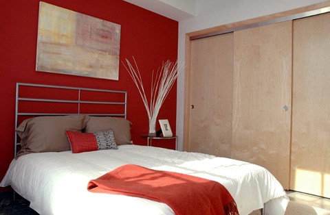 a bedroom with a red wall and a white bed