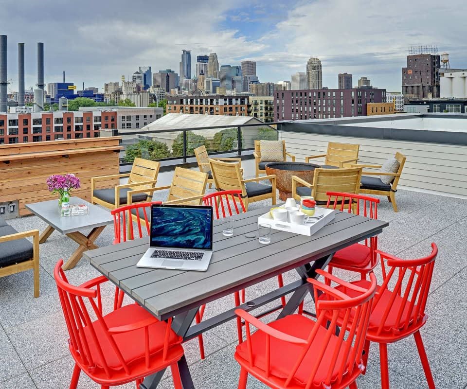 Coze Flats rooftop with downtown skyline view, red high top chairs and outdoor firepit