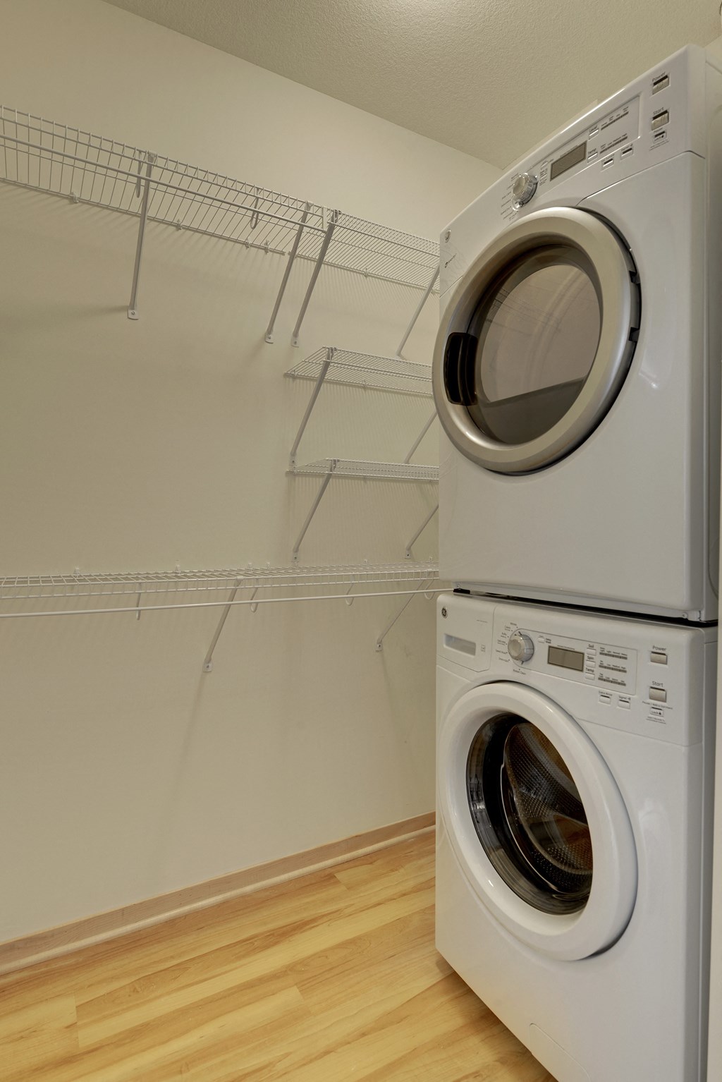 Washer dryer stack in closet with shelving in the Flat D, studio apartment floor plan at Coze Flats