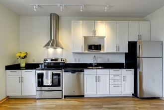 Flat J, 1 bedroom floor plan at Coze Flats, kitchen with white cabinets, stainless steel appliances and black granite countertops - Photo Gallery