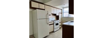 an empty kitchen with white appliances and white cabinets