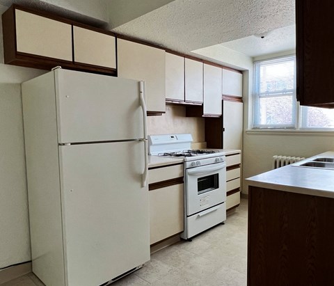 an empty kitchen with white appliances and white cabinets