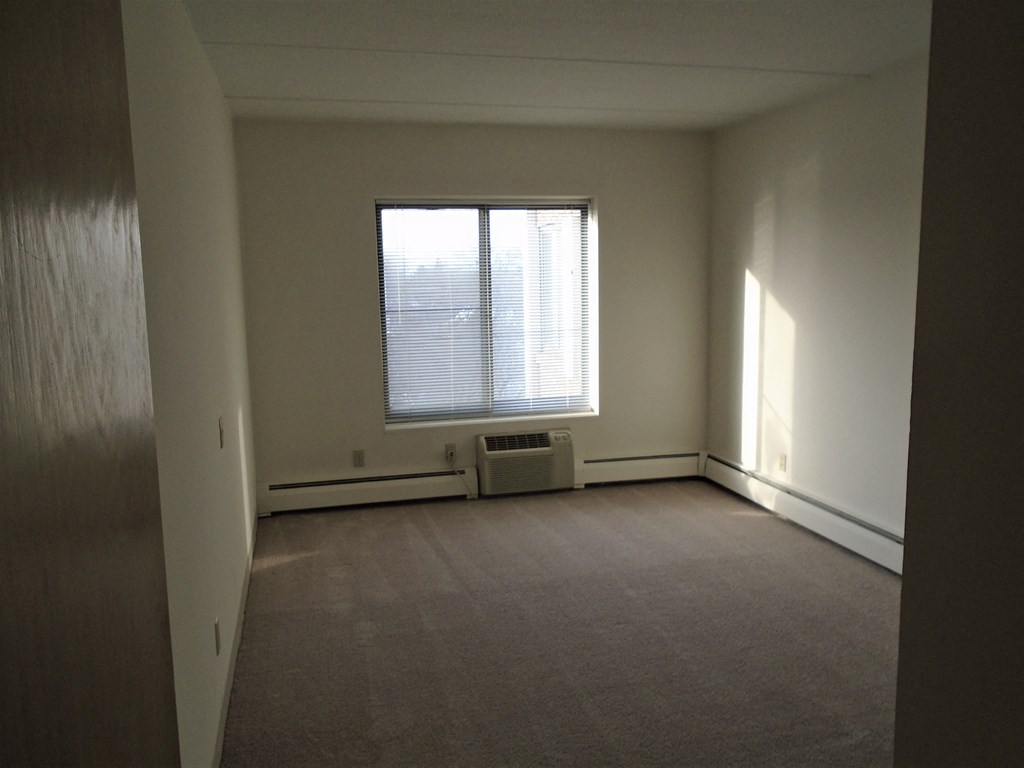 Bedroom photo showing A/C unit and window at John Snell Apartments