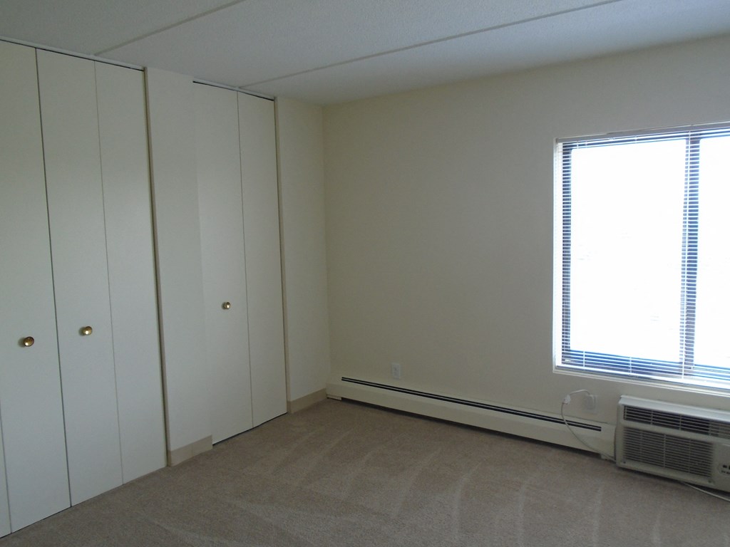 Bedroom photo showing window and closed closet at John Snell Apartments