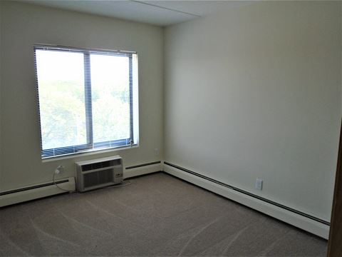 Bedroom photo showing window and A/C unit at John Snell Apartments