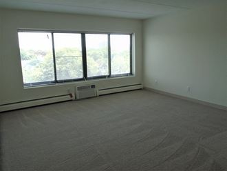 Living area with large window and A/C unit at John Snell Apartments - Photo Gallery 2