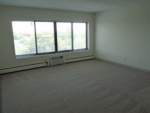 Living area with large window and A/C unit at John Snell Apartments