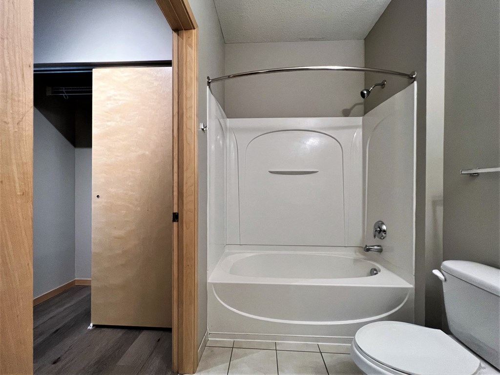 a bathroom with a white toilet next to a white bathtub